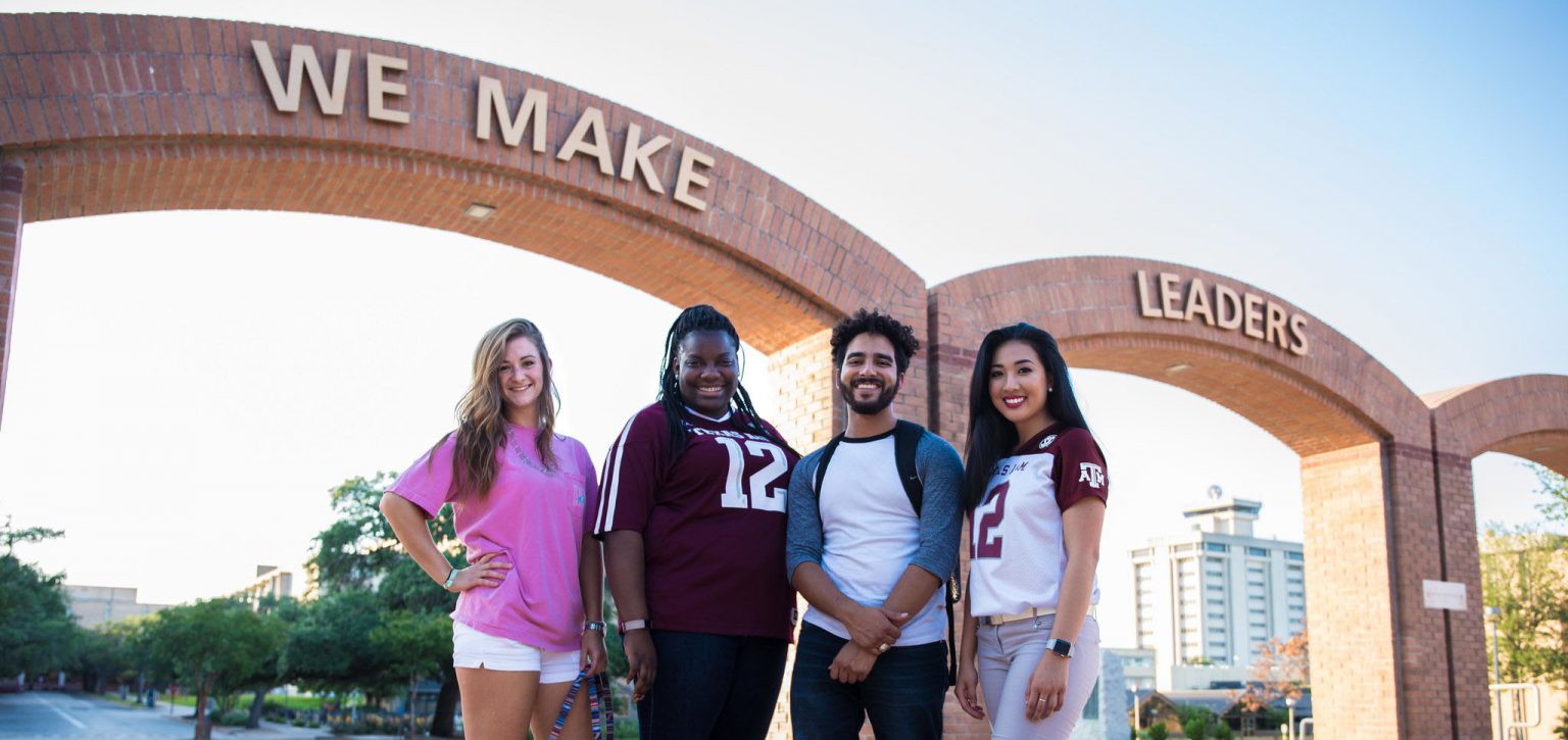 Four diverse students standing in front a sign that says "We Make Leaders"