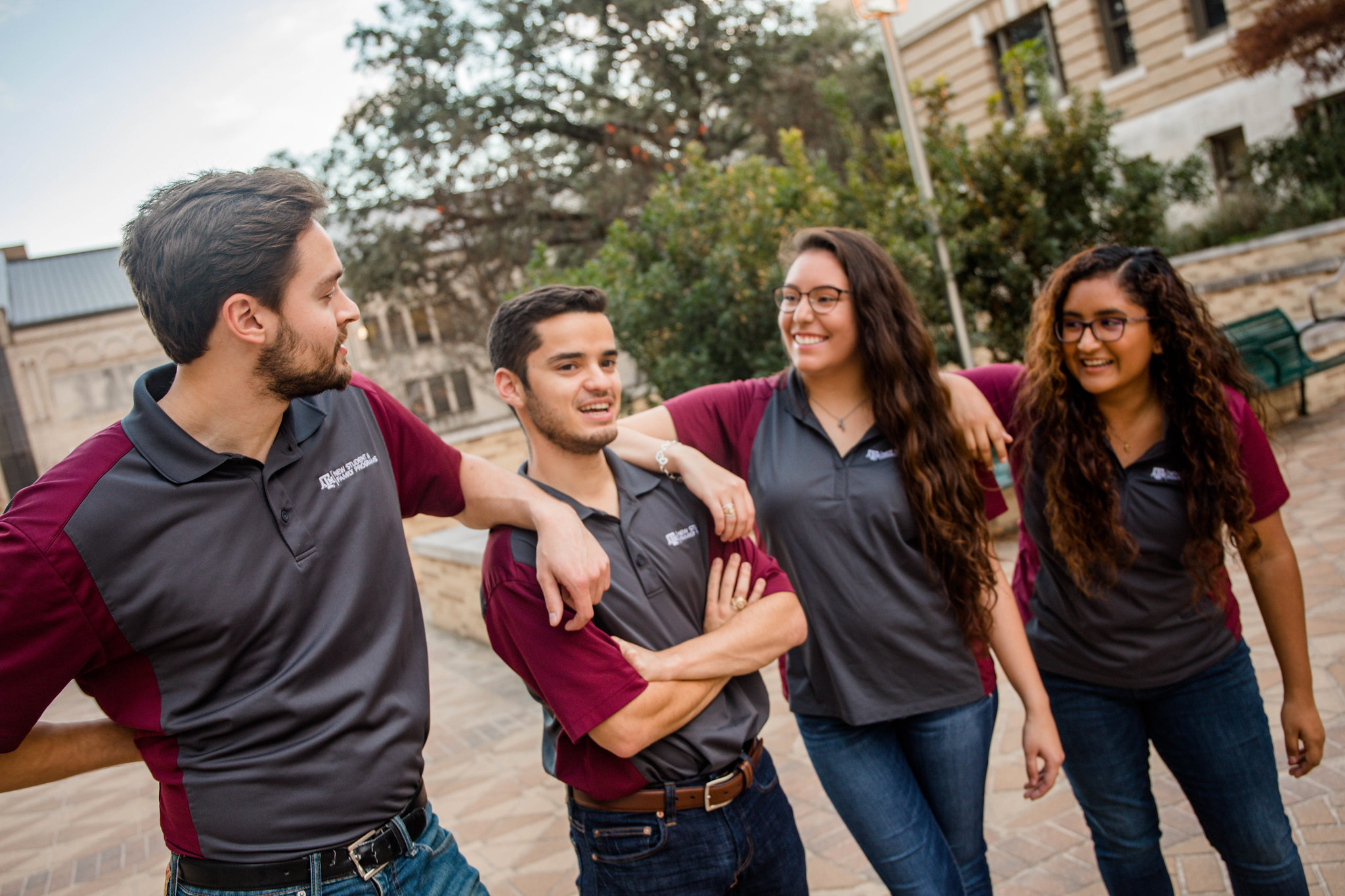 Group of 4 students in Aggie Familia polo shirts. 