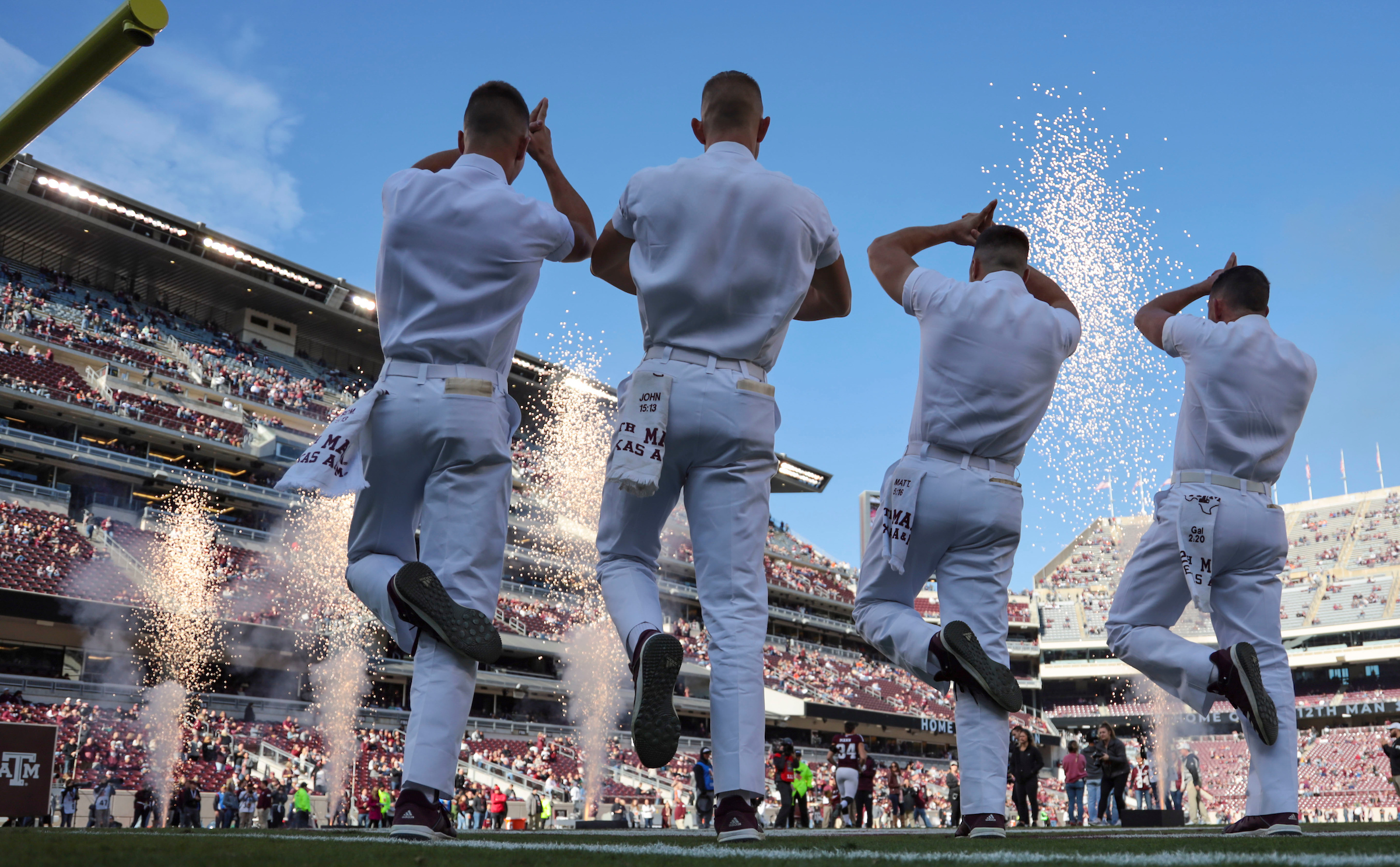 Image of 3 yell leaders leading a yell at a football game. 