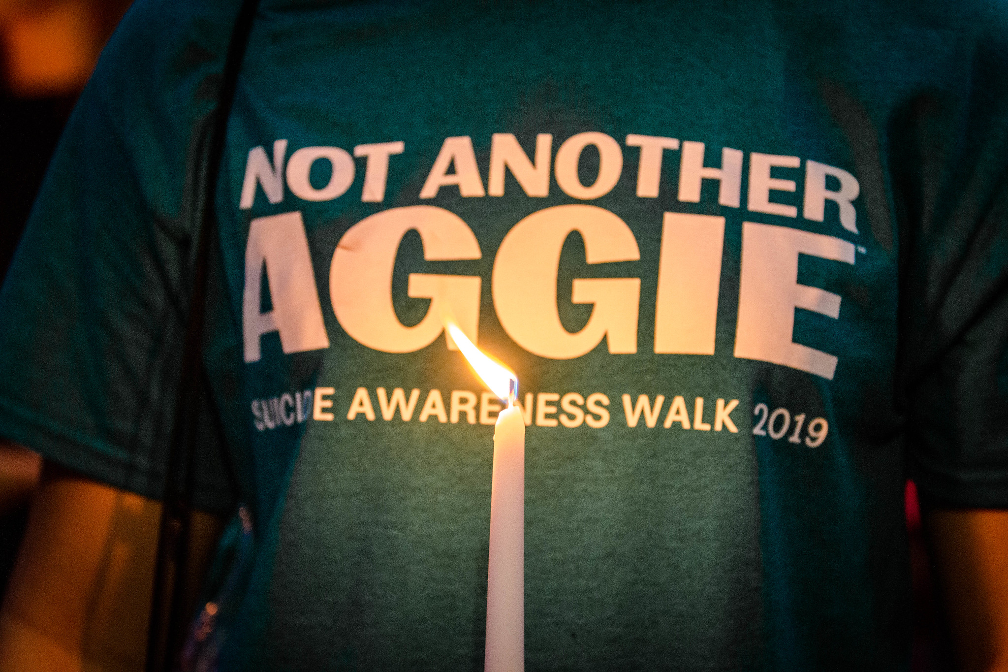 Photo of student holding a candle with a shirt that says Not Another Aggie