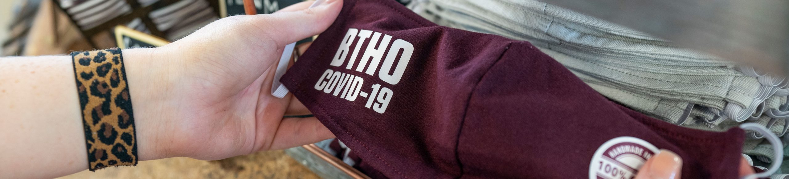 close up of hand holding mask that says BTHO COVID-19
