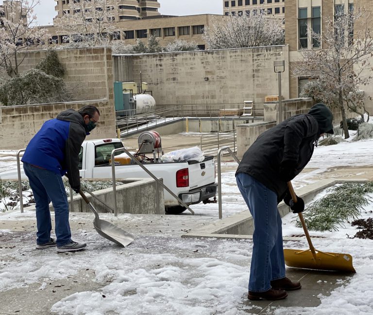 Image of volunteers scraping ice and snow from sidewalks around the Polo road Rec Center