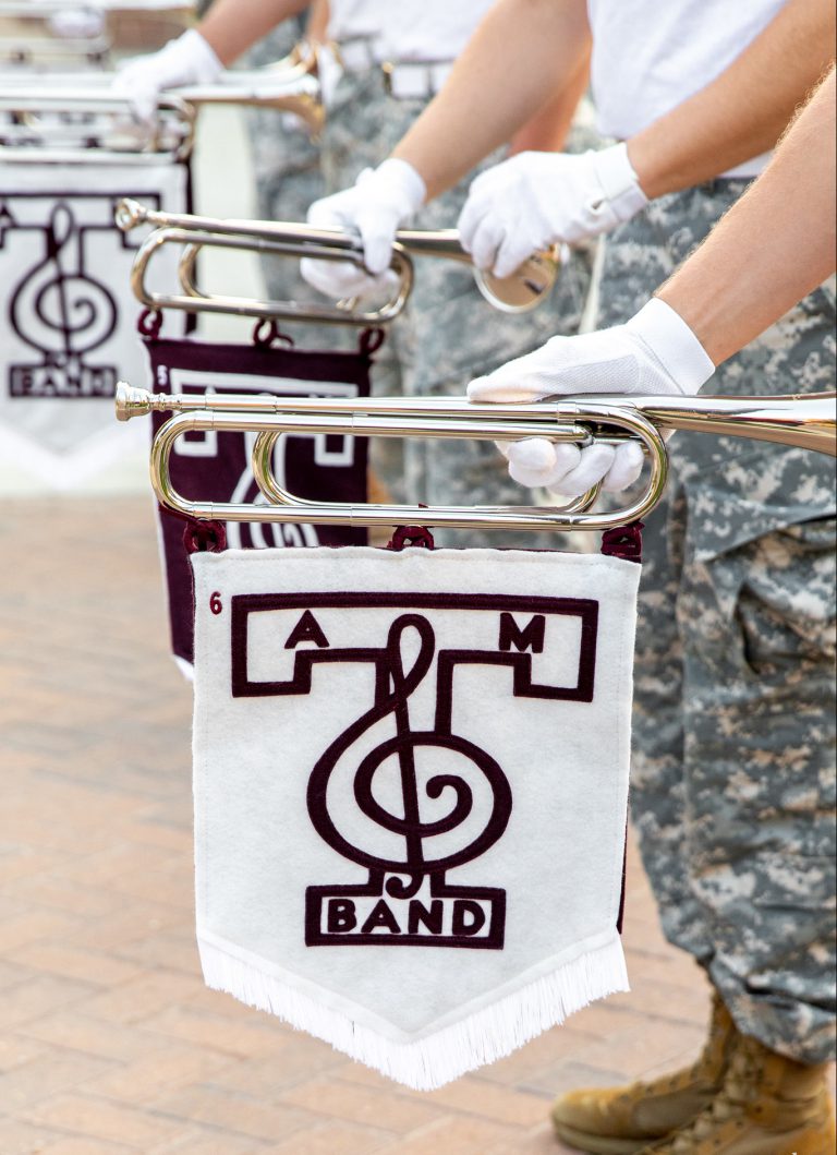 Image of the Fightin' Texas Aggie Band trumpet players holding their trumpets with the band banner attached to them.