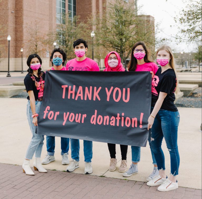 Image of HelpLine student volunteers holding up a banner that says "Thank you for your donation"
