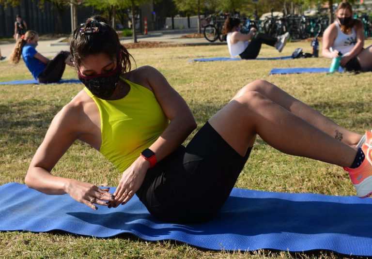 Photo of a student on a mat at an outdoor fitness class