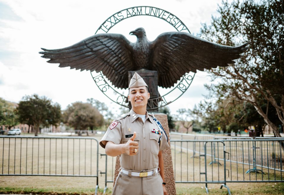 Cadet George Hass stands in front of Eagle statue on Quad in uniform.