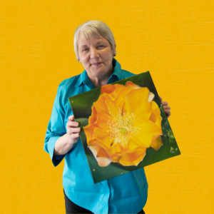photo of Susan Fox-Forrester holding her painting of a flower
