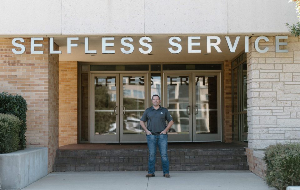 Dave Haney '23 stands in front of the MSC entrance with the words Selfless Service over it.