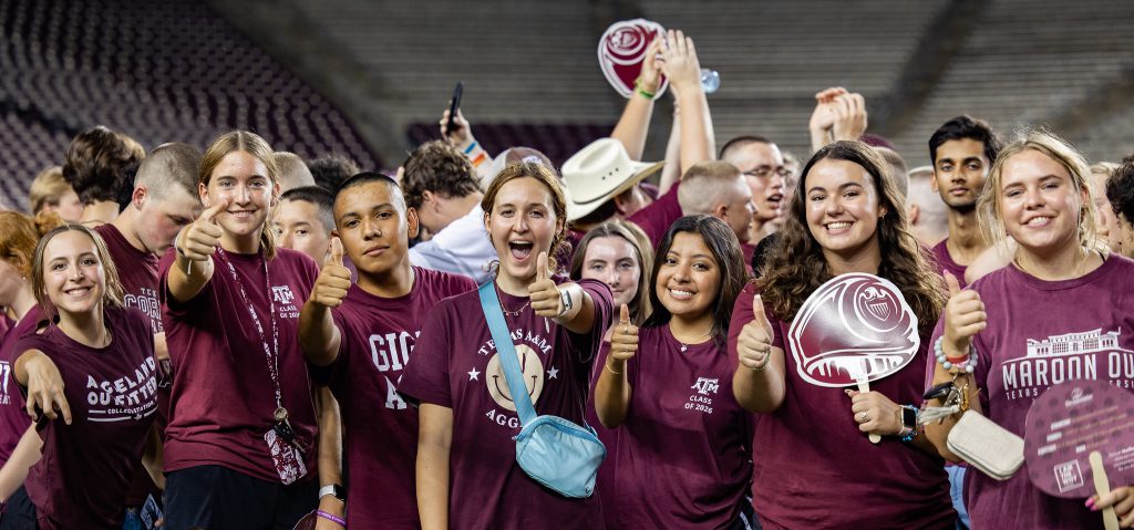 Members of Class of '26 wearing maroon and smile and gig 'em at the camera