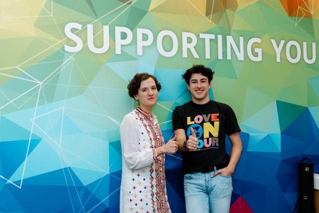 Image of Ben Gettleman ’23 and LGBTQ+ Pride Center Coordinator Frances Jackson in front of the Supporting You mural in the Student Services Building.