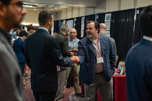 A recruiter at a career fair shakes hands with a student