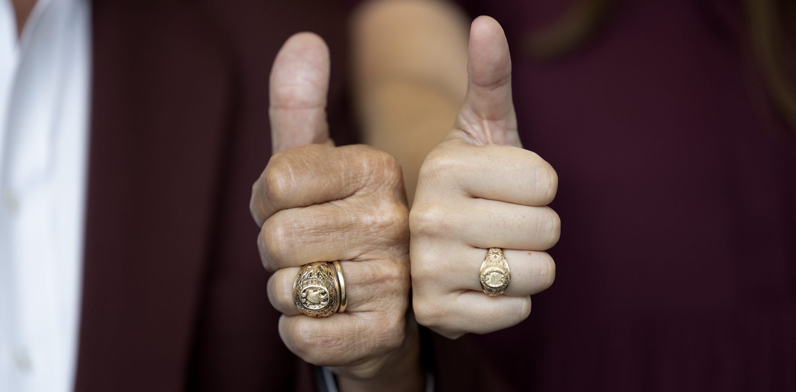 Close-up of two Aggie Rings while giving a Gig 'Em.