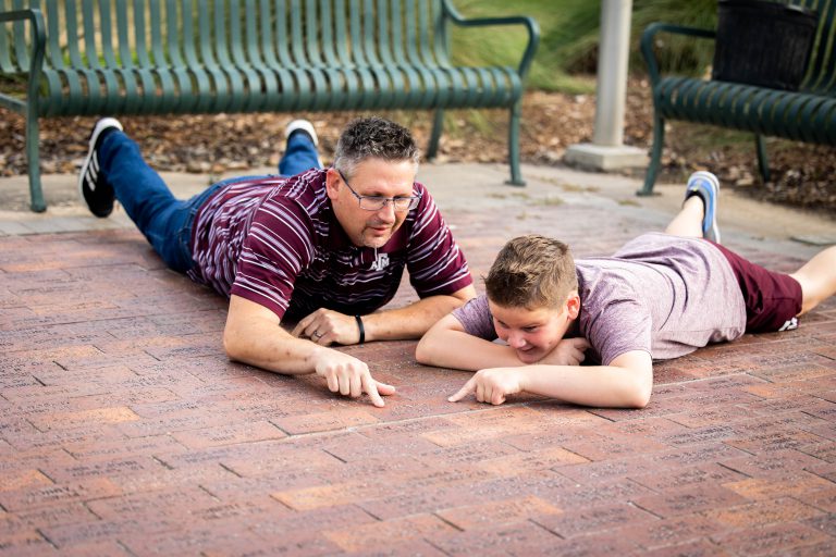 Photo of a boy and his dad looking at the bricks in front of the Corps Center.