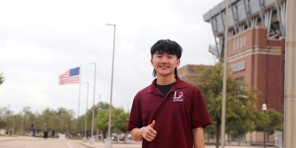 Jisoo Lee stands in front of Kyle Field with a gig 'em