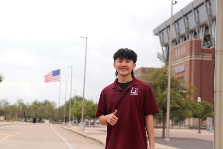 Jisoo Lee stands in front of Kyle Field with a gig 'em
