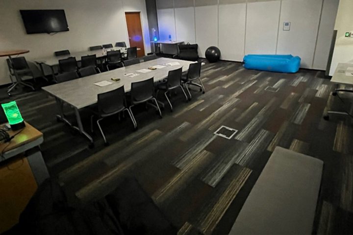 Low light sensory room with tables and comfortable seating for students to decompress in