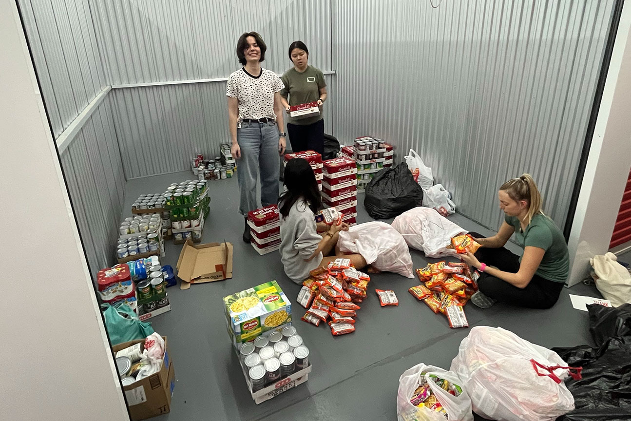 Students inside a storage unit surrounded by food donations