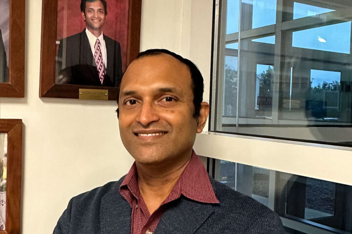 Narayanan standing in front of his picture from when he was the University Apartments Community Council President