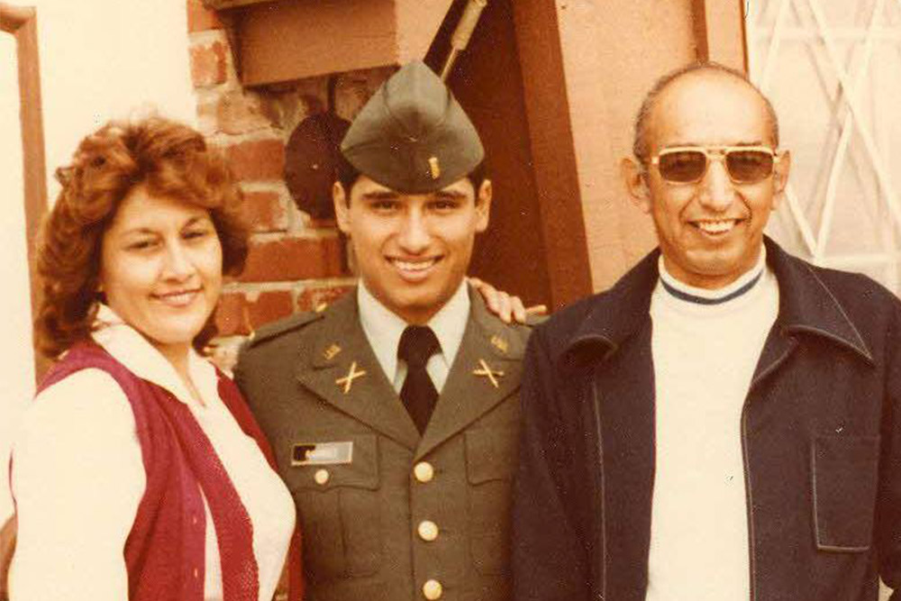 Young Joe Ramirez dressed in a Cops of Cadets uniform posing for a photo with his parents