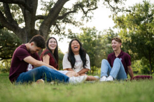 Students sitting in Aggie Park and laughing