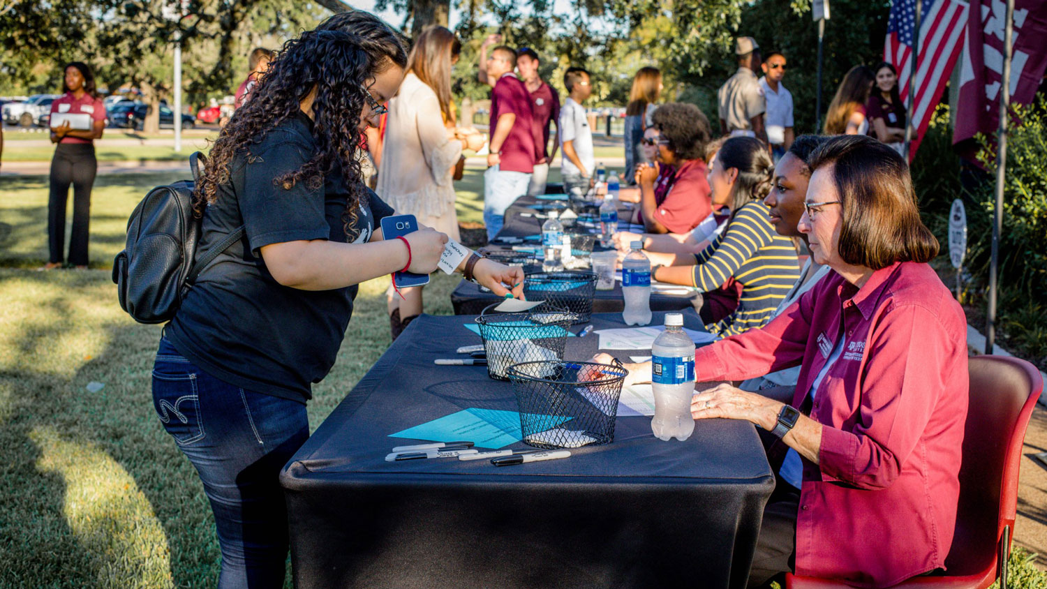 Staff members talking to a student at a tabling event outside.