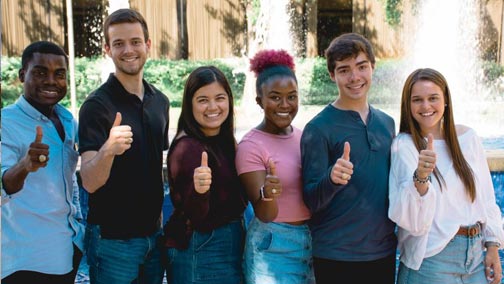 Students giving Gig 'Ems in front of the Rudder Plaza fountain.