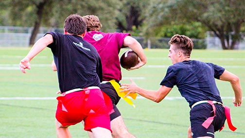Three students playing flag football.