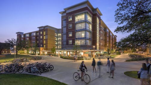 Hullabaloo Hall at twilight with students walking and biking.