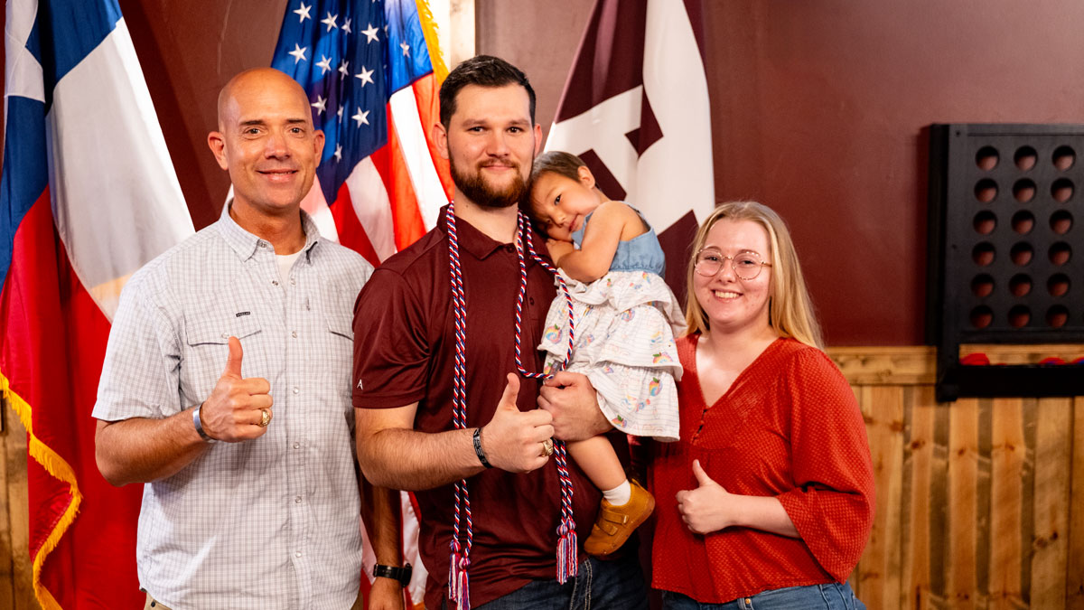 VRSC Director (left) with a student veteran and his family, while he earns his red, white and blue graduation cord.